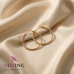 گوشواره حلقه‌ای ژوپینگ طلایی طرح توپی سایز ۳ سانت روی پارچه ساتن کرم